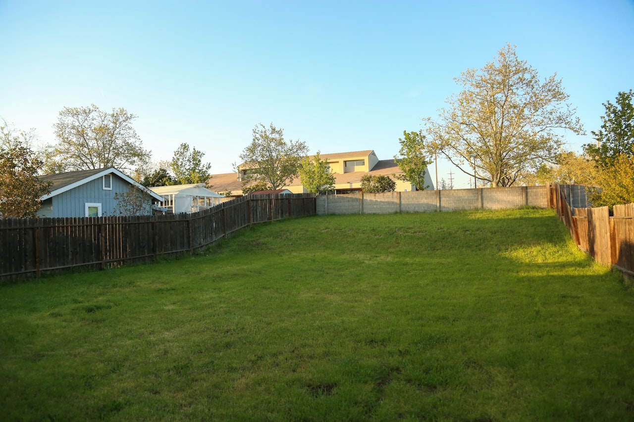 A fenced backyard lawn behind a house
